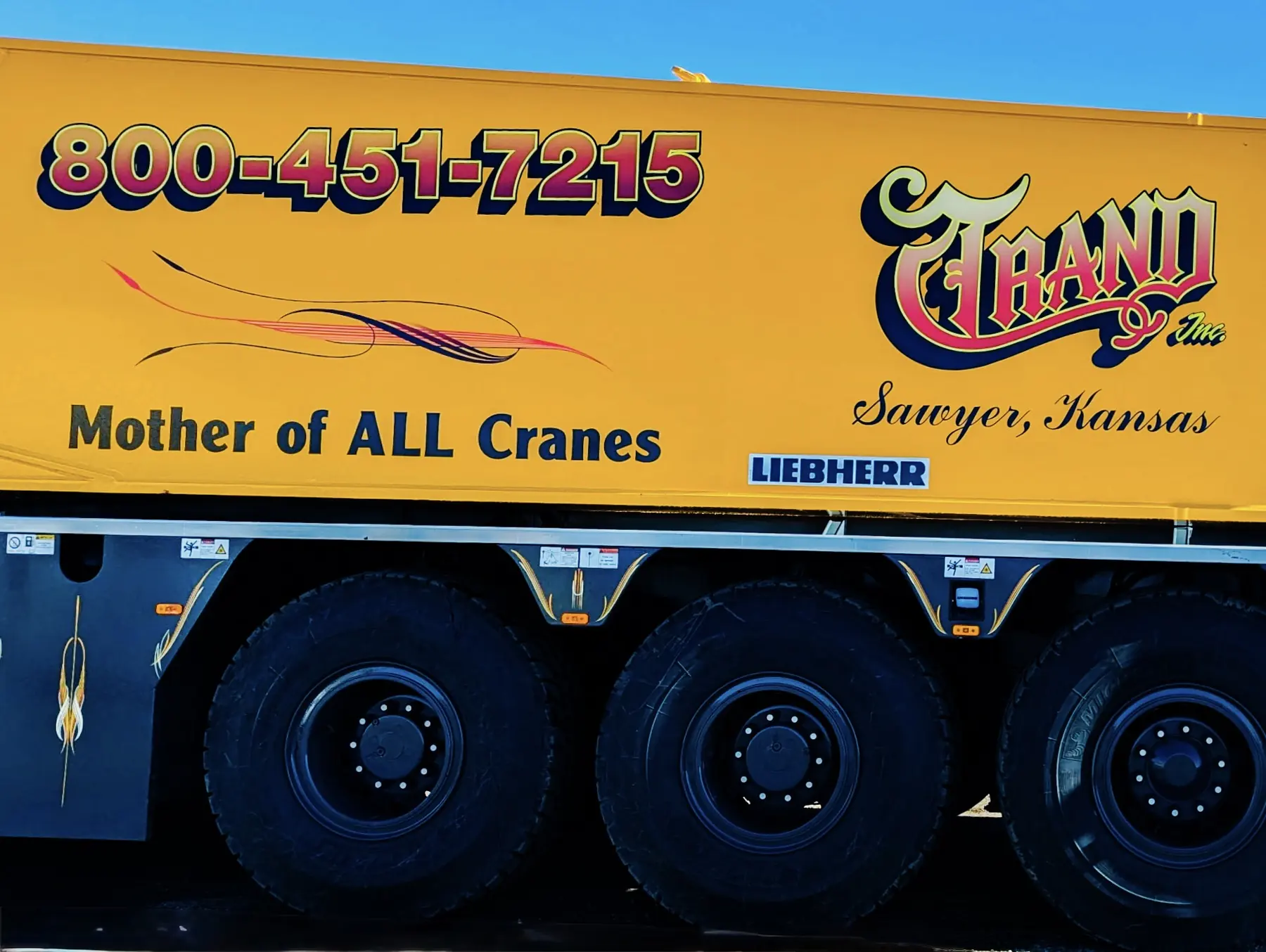 Side of a Trand crane carrier reading Mother of All Cranes