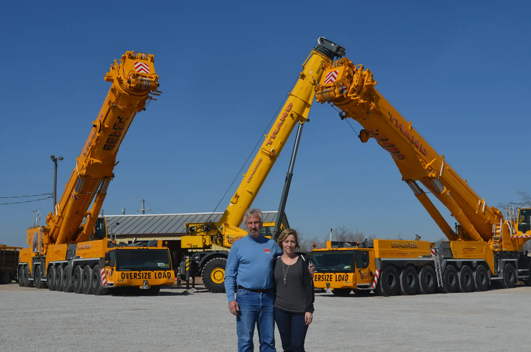 Owners Terry and Sandra Arnett in front of two Trand Liebherr cranes
